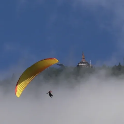 Paraglider boven de wolken bij een bergtop