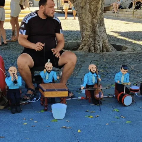Straatmuzikant met een orkest van marionetten