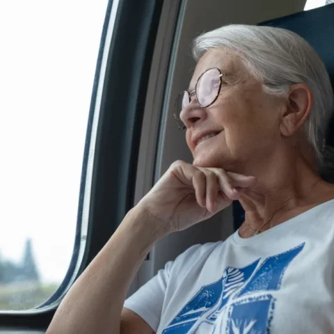 Vrouw kijkt glimlachend uit het treinraam