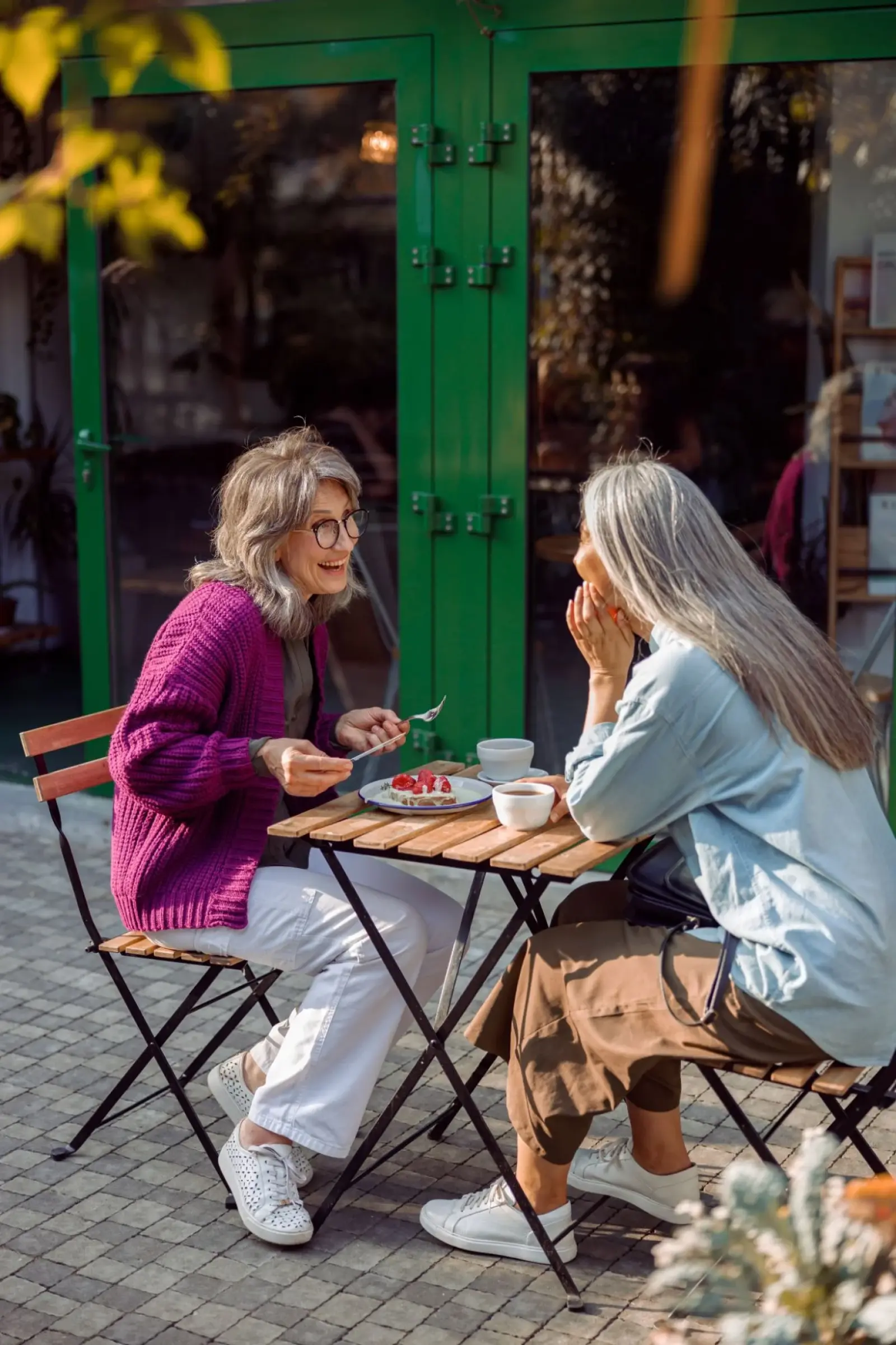 Twee vriendinnen lachen samen op een terras