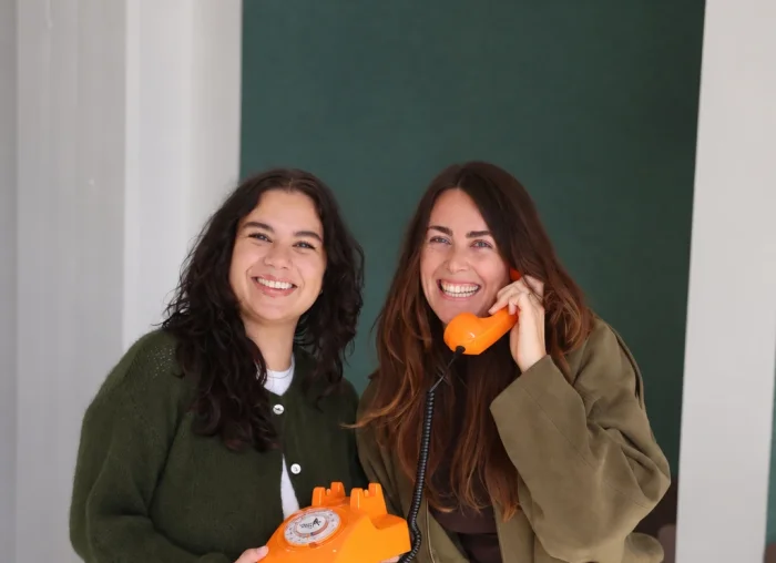 Twee treinspecialisten van Opreis.nl lachend met een oranje telefoon